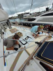 "During"  Applying KiwiGrip Non-Skid on Cabin Top: John and Giddo applying KiwiGrip non-skid.  Water based and dries FAST.  Masking tape has to be removed within a minute or two of the final roll out.  The special course, open weave, roller peaks up the non-skid.
